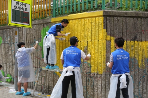 동아쏘시오그룹의 벽화 그리기 봉사활동에 참여한 멘토, 멘티들이 서울청량초등학교 담벼락에 벽화를 그리고 있다.