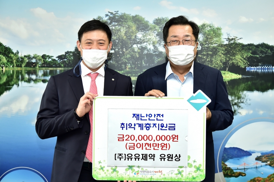 유유제약 유원상 대표이사(왼쪽)가 이상천 제천시장에게 수재의연금을 전달하고 있다.