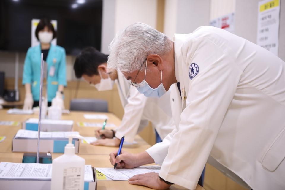 인하대병원 김영모 병원장(앞)과 이진수 감염관리실장(뒤)이 화이자 백신 접종에 앞서 예진표를 작성하고 있다.