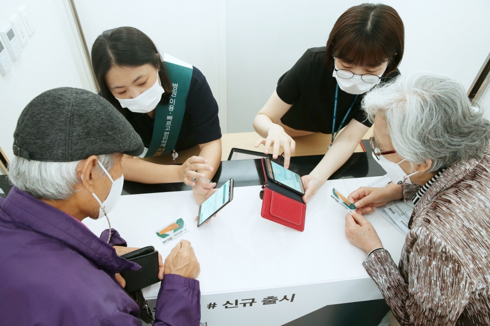 서울아산병원 동관 1층 고객용 모바일 앱 홍보부스에서 70대 부부 환자들이 앱설치와 사용법에 대한 설명을 듣고 있다.