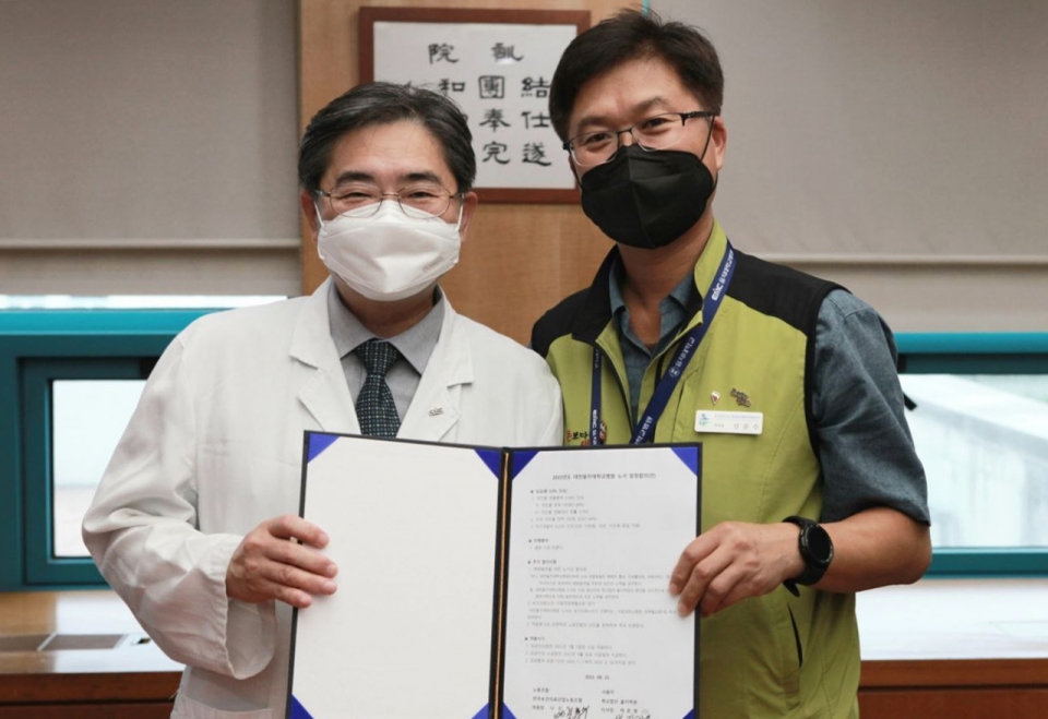 대전을지대학교병원 김하용 병원장(왼쪽)과 신문수 노조 지부장이 25일 단체협상에서 잠정합의안에 서명한 뒤 기념촬영을 하고 있다.